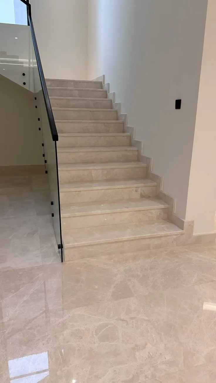 Light beige veined tile stair flight and landing with a black metal railing.